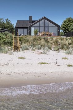 a house sitting on top of a sandy beach next to the ocean