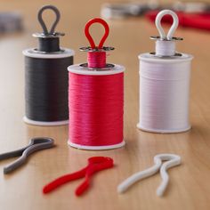 three spools of thread, scissors and pliers sitting on a table next to each other