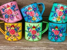 four colorful coffee mugs sitting on top of a wooden table next to each other