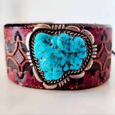 An exquisite sterling turquoise brooch handmade by Navajo artisan L. Smith features a rugged chunk of brilliant blue Kingman turquoise surrounded by a carved platform of sterling silver and paired with a spectacular vintage hand tooled leather belt to be repurposed into a leather bracelet. A deerskin lace wraps around a genuine Indian Head buffalo nickel concho for a comfortable, secure and adjustable tie-on closure. Southwestern Engraved Jewelry For Western-themed Events, Vintage Turquoise Concho Cuff Bracelet, Vintage Turquoise Cuff Bracelet With Concho, Western Turquoise Bracelet With Concho, Western Style Turquoise Bracelet With Concho, Western Turquoise Bracelets With Concho, Western Turquoise Jewelry With Patina, Southwestern Hand Tooled Leather Bracelets, Vintage Hand-tooled Jewelry For Western-themed Events