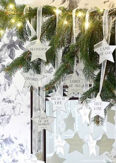 christmas decorations hanging from a tree with white stars and silver ribbons on it's branches