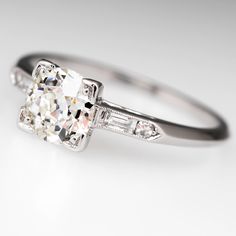 a diamond engagement ring with three baguetts on the side and an old - cut diamond in the middle