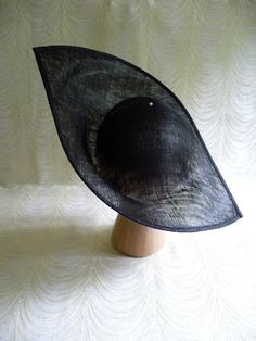 "One large sinamay straw hat base in black in an oblong shape that measures approximately 13\" (33.00 cm) at its widest point and approximately 17\" (43.18 cm) at its longest point. Deep curvature to fit against your head. The stiffened sinamay straw is feather light but has a great sturdy weave that provides excellent support for your millinery creations. Edge finished with sinamay. Shipped in an oversized box, hence the higher than normal postage charge. May have to ship separately for some in Classic Black Boater Hat For Party, Fitted Black Hat For Royal Ascot, Fitted Black Costume Hat For Royal Ascot, Elegant Black Sinamay Hat, Fitted Black Fascinator For Summer, Wide Brim Sinamay Boater Hat For Evening, Black Summer Fascinator, Black Boater Hat For Summer Wedding, Black Curved Brim Boater Hat For Church