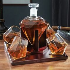 a bottle of perfume sitting on top of a wooden table next to three glass glasses