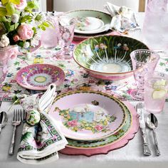 the table is set with pink and green dishes