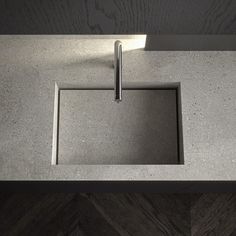 a square sink with a metal faucet in the middle