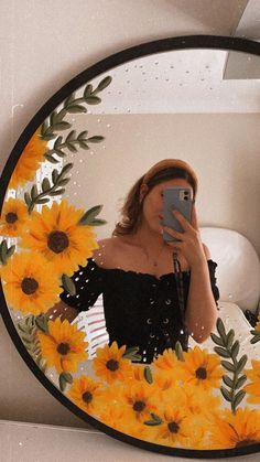 a woman taking a selfie in front of a mirror with sunflowers on it