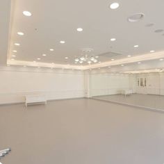 an empty dance studio with white walls and lights on the ceiling is seen in this image