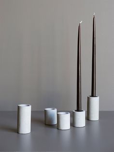 three tall candles sitting next to each other on top of a gray table with one candle in the middle