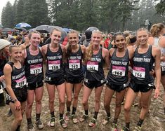 a group of young women standing next to each other on top of a dirt field