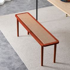 a wooden bench sitting on top of a carpeted floor next to a book shelf