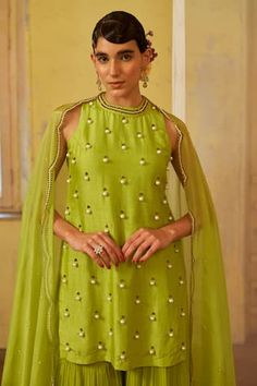 Lime green short kurta with all over butti pattern, contrast pearl and bead embroidery. Paired with pleated tiered flared sharara and pearl work dupatta.
Components: 3
Pattern: Embroidered
Type Of Work: Pearl and Bead Work
Neckline: Round Neck
Sleeve Type: Sleeveless
Fabric: Kurta: Dupion Silk, Sharara and Dupatta: Georgette
Color: Green
Other Details: 
Scalloped cut work dupatta border
Keyhole back
Model height: 5ft 8inches, wearing size S
Closure: Kurta: Back hook and eye
Occasion: Mehendi and Embellished Green Palazzo Set For Eid, Green Sleeveless Dress For Diwali, Sleeveless Green Sets For Reception, Green Sleeveless Sets For Reception, Green Sleeveless Kurta For Diwali, Sleeveless Green Sharara For Reception, Elegant Green Dress With Gota Work, Sleeveless Green Palazzo Set For Wedding, Green Sleeveless Wedding Sets