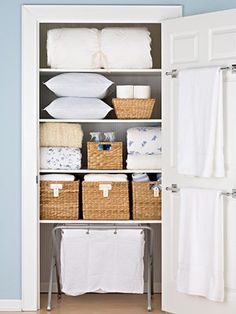 an open closet filled with lots of white linens and folded towels next to baskets