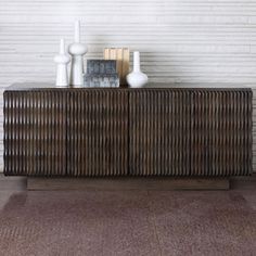 a wooden sideboard with two vases on top of it next to a brick wall