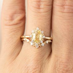 a woman's hand with a yellow and white diamond ring on top of her finger