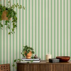 a green striped wallpaper in a living room next to a wooden table with a potted plant on it