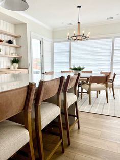 a dining room table with chairs and a chandelier hanging from it's ceiling