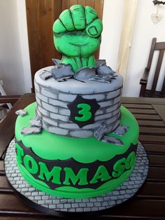 a green and black cake with a fist on top