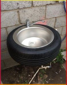 a close up of a tire on the ground next to a brick wall and a planter