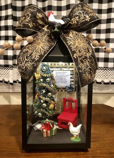 a christmas display case with a bird on top and presents in the bottom, sitting on a table