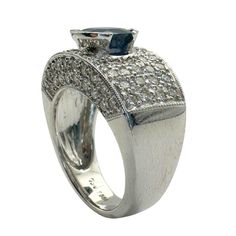 Indulge in luxury with our 18k Diamond and Sapphire Wide Band Ring. Featuring 1.40 carats of sparkling diamonds and a stunning 1.80 carat sapphire center, this sleek and modern ring is crafted in 18k white gold. With a weight of 5.6 grams and a size 6.50, it's the perfect statement piece for a sophisticated and exclusive look.   Condition: In good condition with some minor surface wear consistent with age. Ring size: 6.50 Markings: "750" "T864" "18k" Metal: 18k White Gold Weight: 5.6 grams Diamonds: 1.40 carats  Sapphire: 1.80 carats Formal Platinum Sapphire Ring With Pave Setting, Oval Sapphire Ring With Pave Setting In Platinum, Platinum Sapphire Ring With Pave Setting In White Gold, Luxury Sapphire Ring With Brilliant And Baguette Cuts, Elegant Round Sapphire Ring In Platinum With Pave Setting, Round Sapphire Ring With Pave Setting In Platinum, Platinum Sapphire Ring With Pave Setting, Formal Sapphire Ring With Pave Setting, Luxury Diamond White Baguette Cut Sapphire Ring