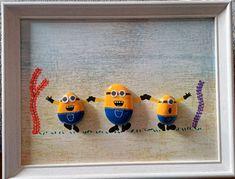 three yellow and blue minion magnets in a white frame