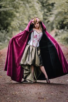 a woman in a costume is standing on the road with her cape over her head