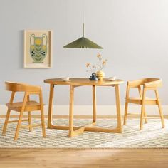 a table and two chairs in a room with a rug on the floor next to it