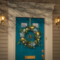 a blue front door with a wreath on it and two lights hanging from the side