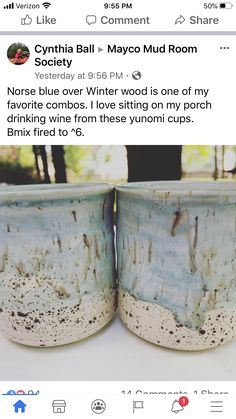 two mugs sitting next to each other on top of a white table with trees in the background