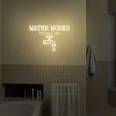 a bathroom with a bathtub, towel rack and neon sign above it that reads water works price $ 150