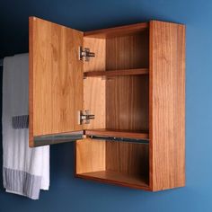 a wooden cabinet hanging on the wall next to a towel rack with two towels in it