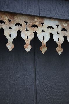 an old metal object hanging from the side of a building