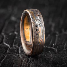 "* Price may vary depending on ring size, please inquire with us directly with your needed size for accurate pricing! This rustic but elegant feeling Mokume Gane ring is shown in the Twist pattern and our Firestorm metal combination, with a low dome profile, etched and oxidized finish, and flush set diamonds. The Firestorm palette features 14kt yellow gold, 14kt red gold, palladium and sterling silver.  Palette: Firestorm Pattern: Twist Width Shown: 6mm Size Shown: 9 Finish: Etched & Oxidized Profile: Low Dome Stones: Center- 2.5mm Square Diamond, Sides- 6 1mm Round Black Diamonds Setting Style: Flush  Price does NOT include stones or setting fee, please inquire with us directly for a quote.  We care about customer service and would like to hear from you! Please contact us to help create y Silver Palette, Mokume Gane Ring, Flush Set Diamond, Twisted Band Ring, Twist Pattern, Mokume Gane, Twisted Band, Square Diamond, Diamond Settings