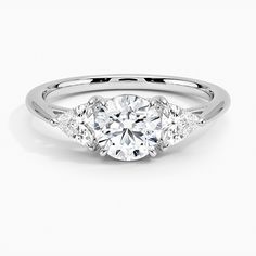 a three stone engagement ring with diamonds on the sides and an oval diamond in the center