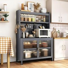 a kitchen area with a microwave, cabinets and table cloths on the counter top