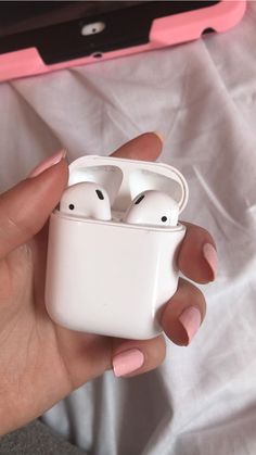 a person holding an apple airpods in their left hand, with the case open