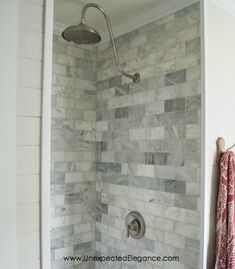 a bathroom with a shower head and marble tile on the walls, along with a towel rack