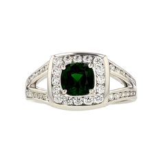 a ring with a green stone surrounded by white diamonds on the sides and in the middle