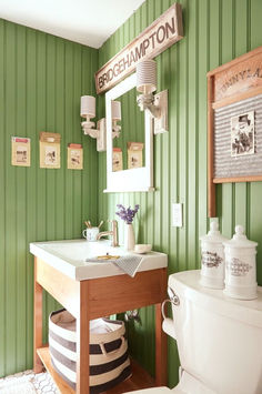 a bathroom with green walls and striped rugs on the floor, along with a white toilet