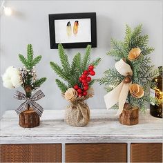 three vases filled with flowers on top of a wooden table next to a christmas tree