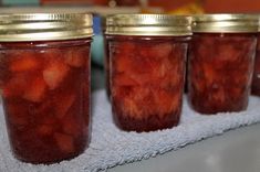 four jars filled with pickles sitting on top of a towel