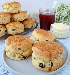 several biscuits on a plate with butter and jam in the backgroung behind them