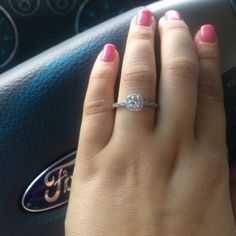 a woman's hand with a diamond ring on her finger in front of a steering wheel