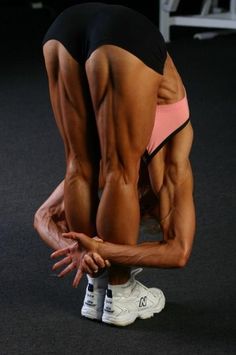 a female bodybuilt is bent over with her hands on the ground in front of her