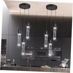 a modern kitchen with black cabinets and lights hanging from the ceiling over the stove top