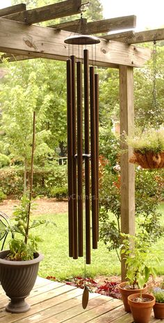 a wind chime hanging from the side of a wooden deck next to potted plants