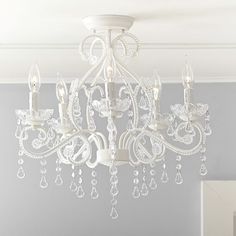 a white chandelier hanging from the ceiling in a room with gray walls and furniture