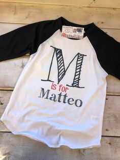 This listing includes one UNISEX 3/4 sleeve raglan baseball tee OR standard white short sleeve tee in youth or toddler. Scribble Letter With Your Little One's Name.. PLEASE include the name and letter as you wish it to be printed into order notes.. We absolutely love this brand of tee's... They will not shrink and hold up great for daily wear. The material is incredibly soft and the design is dyed into the fabric. No more peeling or cracking like vinyl or screen printing. Our process allows the White Cotton Tops With Baseball Collar, White Cotton Baseball Jersey For Baseball Season, White Cotton Baseball Jersey, White T-shirt With Baseball Collar And Pre-shrunk, White Baseball Collar Top With Team Name, White Cotton Baseball Jersey With Raglan Sleeves, White Shirt With School Spirit For Spring, White Baseball Collar T-shirt With Letter Print, White T-shirt With Letter Print And Baseball Collar