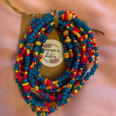 multicolored beaded bracelets are displayed on a piece of cloth with a tag attached to it